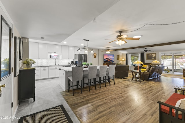 kitchen featuring tasteful backsplash, white cabinets, stainless steel fridge with ice dispenser, a center island, and hanging light fixtures