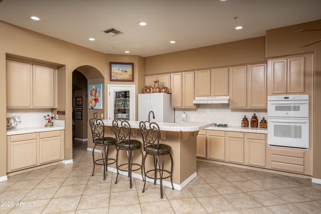 8698 E Preserve Way, Scottsdale, AZ 85266 - kitchen with tile countertops, white appliances, arched walkways, tasteful backsplash, and a breakfast bar area