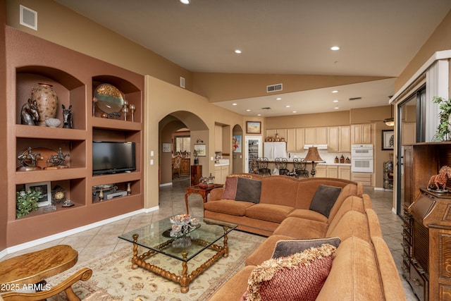 8698 E Preserve Way, Scottsdale, AZ 85266 - living room featuring arched walkways, built in shelves, lofted ceiling, light tile patterned floors, and recessed lighting