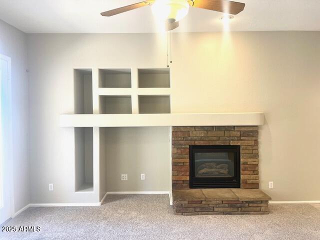 unfurnished living room with ceiling fan, carpet flooring, and a stone fireplace