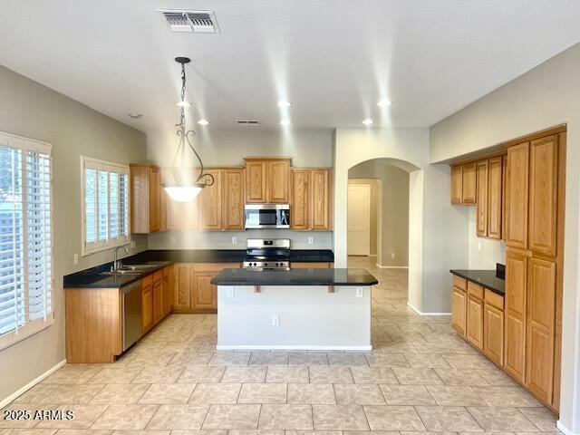 kitchen featuring pendant lighting, stainless steel appliances, sink, and a kitchen island