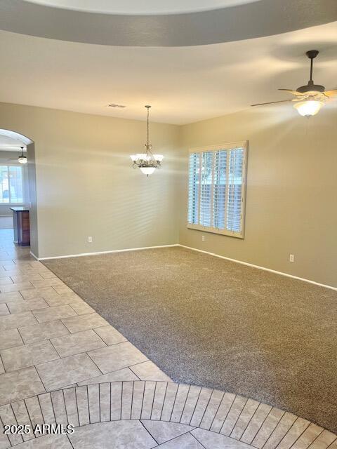 carpeted empty room with ceiling fan with notable chandelier