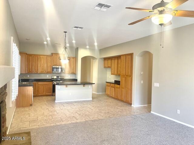 kitchen featuring a stone fireplace, a center island, light carpet, pendant lighting, and stainless steel appliances