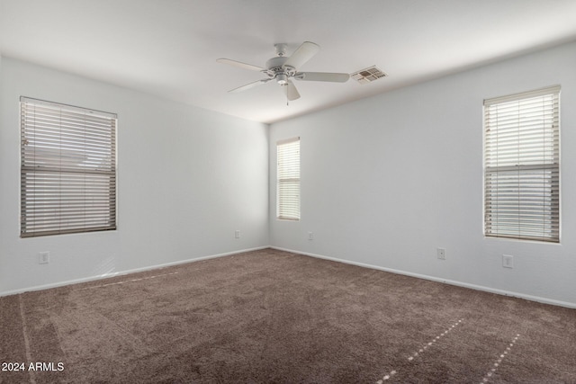 carpeted empty room with ceiling fan and plenty of natural light