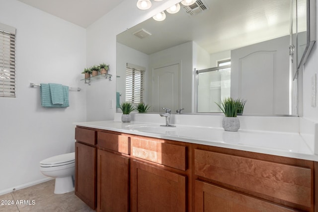 bathroom with tile patterned flooring, vanity, a shower with door, and toilet