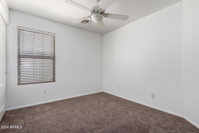 spare room with ceiling fan and dark colored carpet