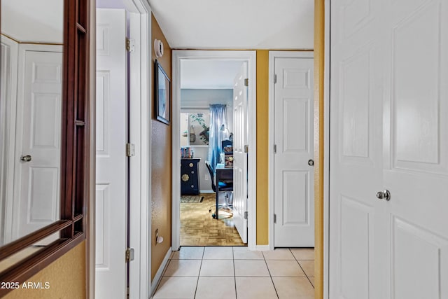 corridor with light tile patterned flooring and baseboards