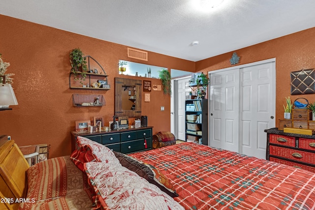 bedroom with a closet, visible vents, a textured wall, and a textured ceiling