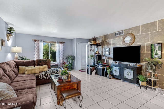 living room with light tile patterned floors, tile walls, visible vents, and a textured ceiling