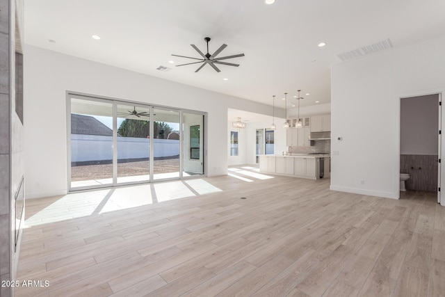 unfurnished living room featuring ceiling fan, light hardwood / wood-style flooring, and sink