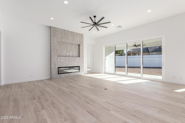 unfurnished living room featuring light wood-type flooring, ceiling fan, and a fireplace