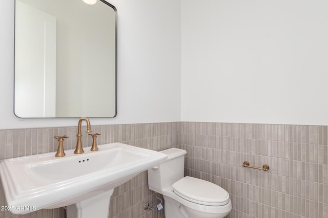 bathroom with sink, tile walls, and toilet