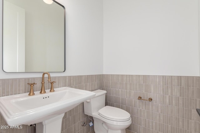 bathroom featuring sink, tile walls, and toilet