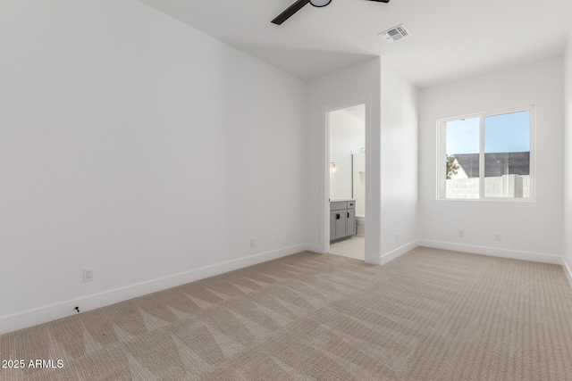 unfurnished bedroom featuring ensuite bath, light colored carpet, and ceiling fan