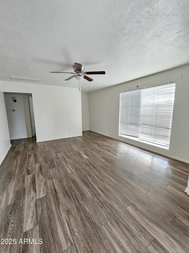 empty room with ceiling fan, dark wood-type flooring, and a textured ceiling