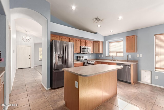 kitchen with light tile patterned floors, a center island, stainless steel appliances, and vaulted ceiling