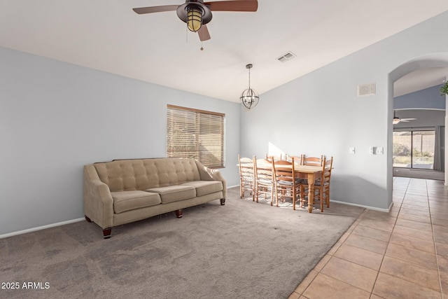 tiled living room with ceiling fan with notable chandelier