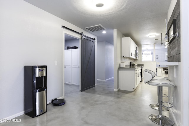 kitchen featuring a barn door, white cabinets, a textured ceiling, and appliances with stainless steel finishes