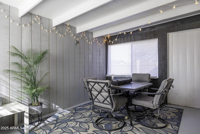 dining room featuring beamed ceiling, a chandelier, and wooden walls