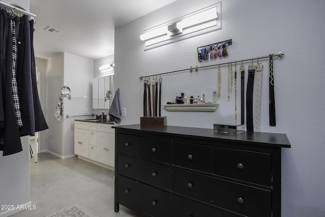 interior space featuring vanity, concrete flooring, and a textured ceiling