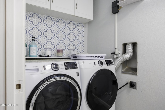 clothes washing area with washer and dryer and cabinets