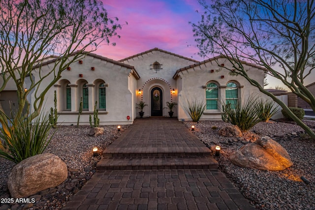 mediterranean / spanish house featuring stucco siding and a tiled roof