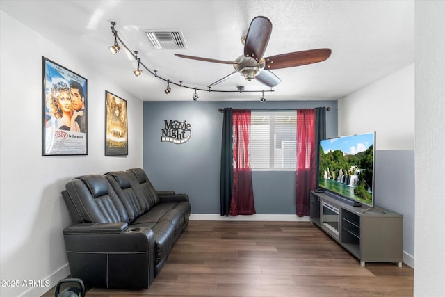 living room with ceiling fan, track lighting, and dark hardwood / wood-style flooring