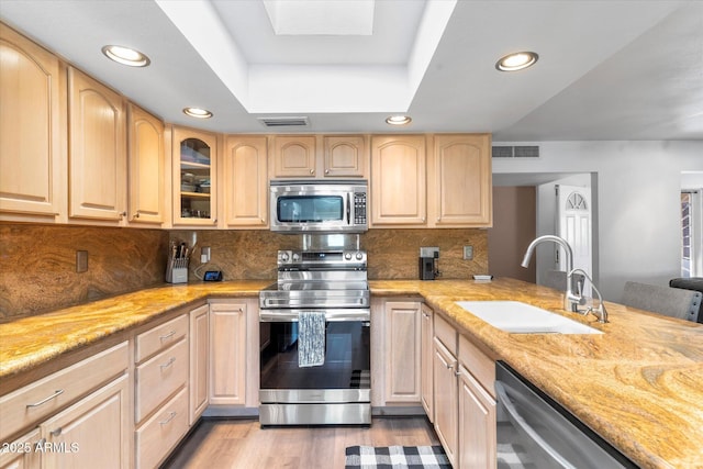 kitchen featuring light brown cabinetry, sink, stainless steel appliances, and light stone countertops