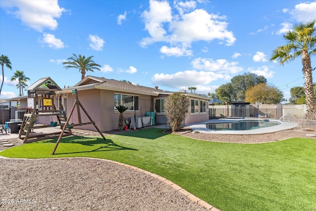 back of property featuring a playground, a yard, and a fenced in pool