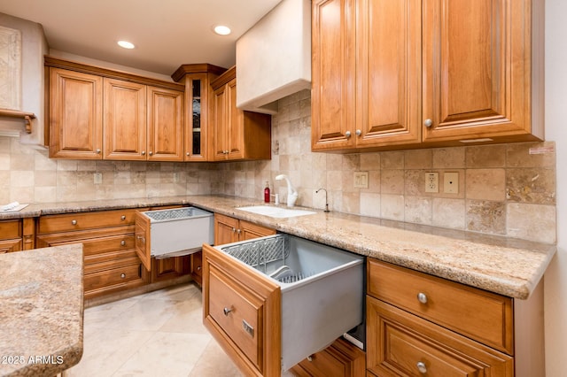 kitchen with light stone countertops, sink, and decorative backsplash