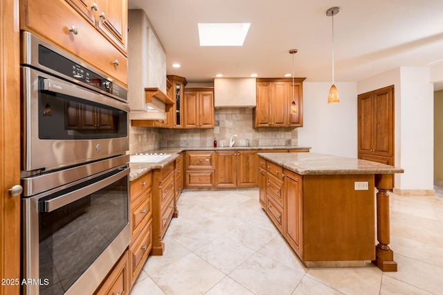 kitchen featuring pendant lighting, decorative backsplash, a center island, light stone countertops, and stainless steel double oven