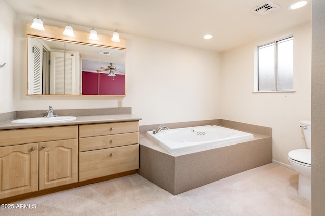 bathroom featuring vanity, tiled tub, and toilet