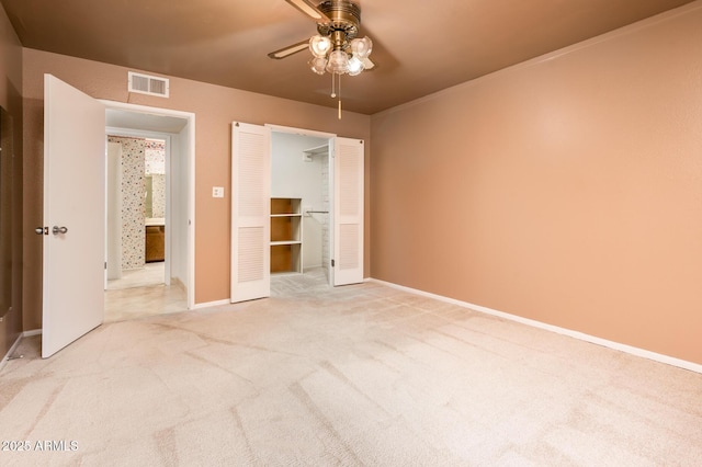 unfurnished bedroom with a walk in closet, light colored carpet, ceiling fan, and a closet