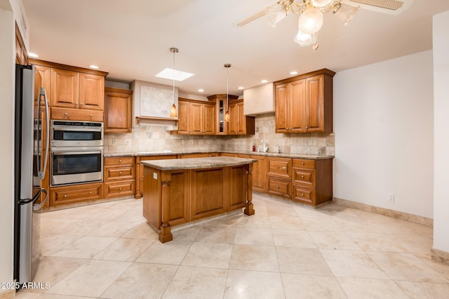 kitchen with a kitchen island, pendant lighting, tasteful backsplash, light stone counters, and stainless steel appliances