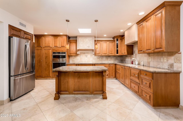 kitchen featuring light stone countertops, decorative light fixtures, stainless steel appliances, and a center island