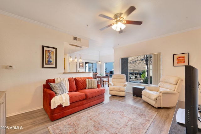 living room featuring visible vents, ornamental molding, wood finished floors, baseboards, and a ceiling fan