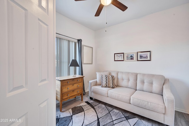 living area with a ceiling fan, baseboards, and wood finished floors