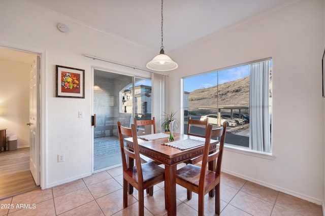 dining space featuring crown molding, baseboards, and light tile patterned flooring