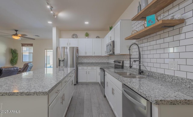 kitchen with stainless steel appliances, white cabinetry, light stone countertops, and backsplash