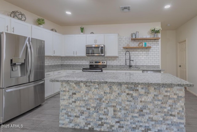 kitchen featuring white cabinetry, appliances with stainless steel finishes, a center island, and sink