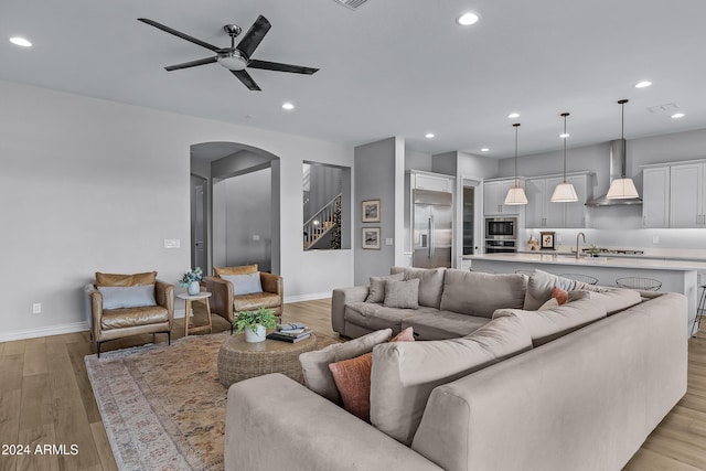 living room with ceiling fan, light hardwood / wood-style flooring, and sink