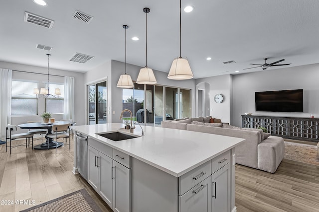 kitchen featuring ceiling fan with notable chandelier, sink, an island with sink, and decorative light fixtures