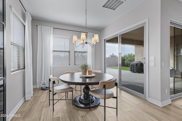 dining space featuring light hardwood / wood-style floors, an inviting chandelier, and a wealth of natural light