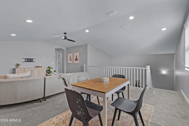 carpeted dining space with ceiling fan and vaulted ceiling