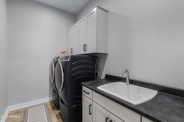 washroom featuring cabinets, independent washer and dryer, sink, and light hardwood / wood-style flooring