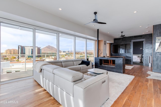 living room featuring a ceiling fan, wood finished floors, a view of city, recessed lighting, and a fireplace