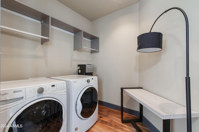 clothes washing area with washer and dryer, light wood-style flooring, and baseboards