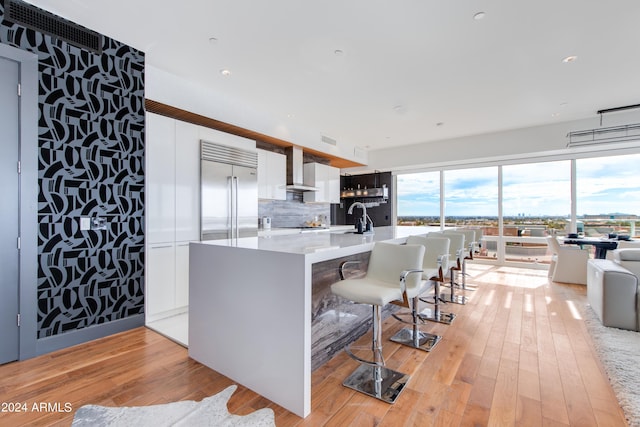 kitchen with built in refrigerator, white cabinets, tasteful backsplash, light wood-style floors, and light countertops