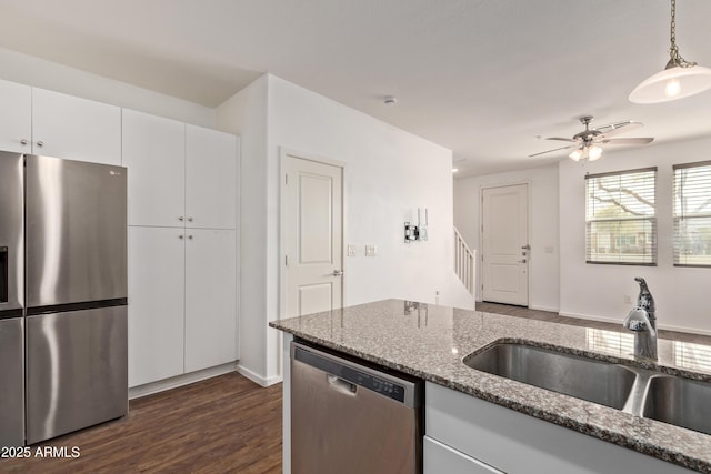 kitchen featuring a ceiling fan, stone counters, dark wood finished floors, a sink, and appliances with stainless steel finishes