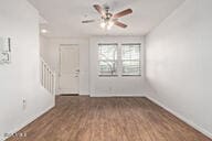 interior space featuring stairs, wood finished floors, a ceiling fan, and baseboards